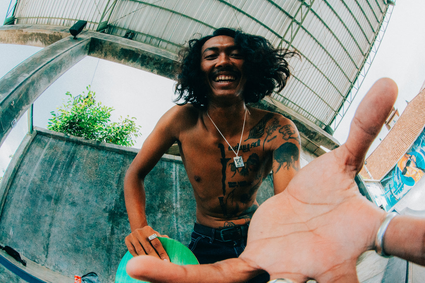 Skateboarder at Skatepark reaching at camera holding a skateboard in left hand wearing Black Cat Pendant Necklace on a Silver Chain
