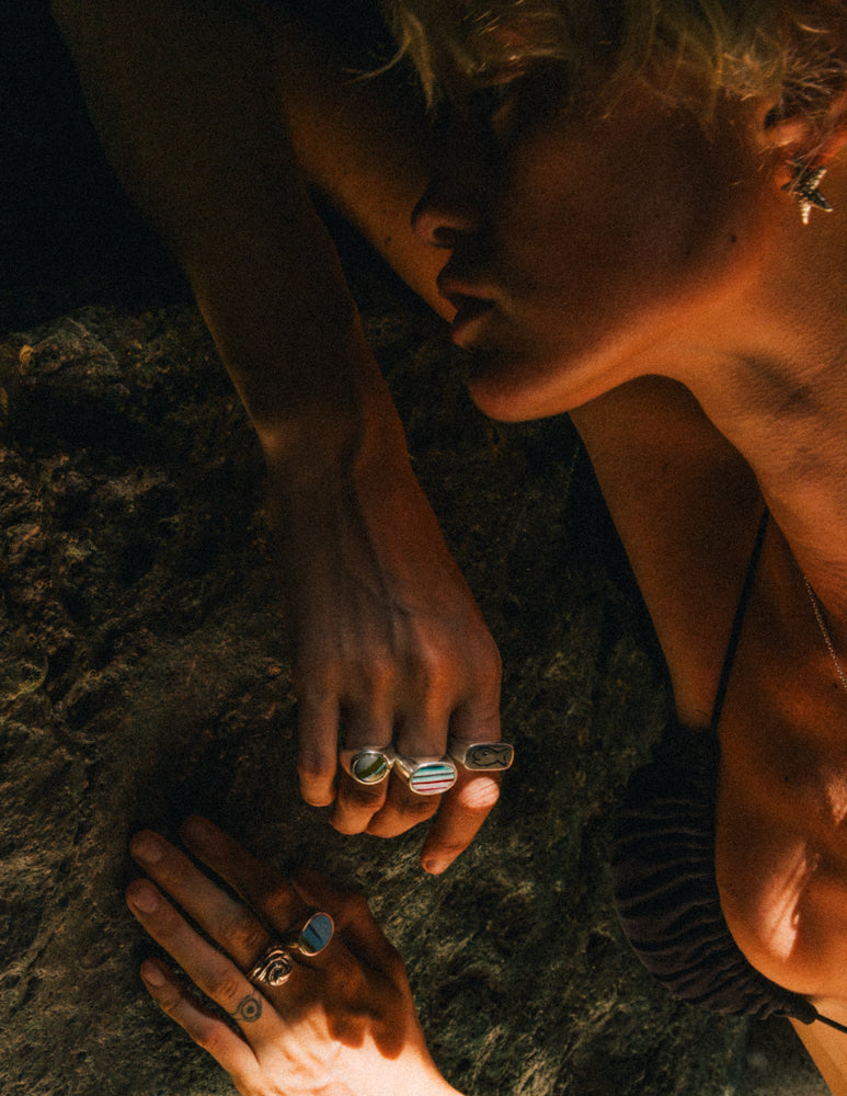 Modeling leaning against a Rock in a Sunny Cave in Sumba, Indonesia. Her hand positioning is highlighting the Surfite Ring Collection, the Badfish Ring, and the Tidal Wave Ring in Sterling Silver. She is also wearing the Sterling Silver Starfish Earrings. All of the Jewelry is handmade.