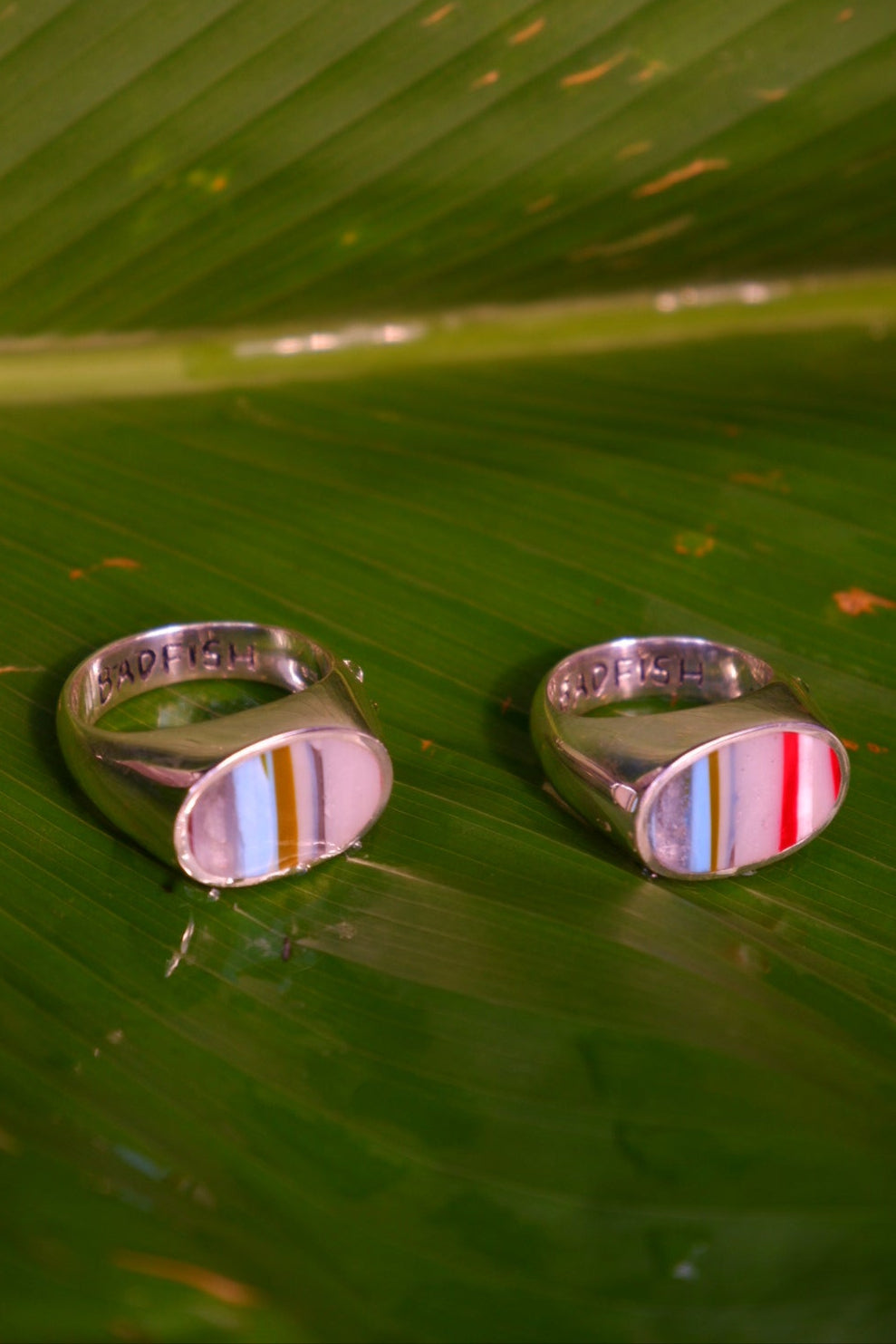 Semi Side Perspective of Two Multicolored Recycled Surfboard Resin Scrap Stones Set in Sterling Silver Signet Rings