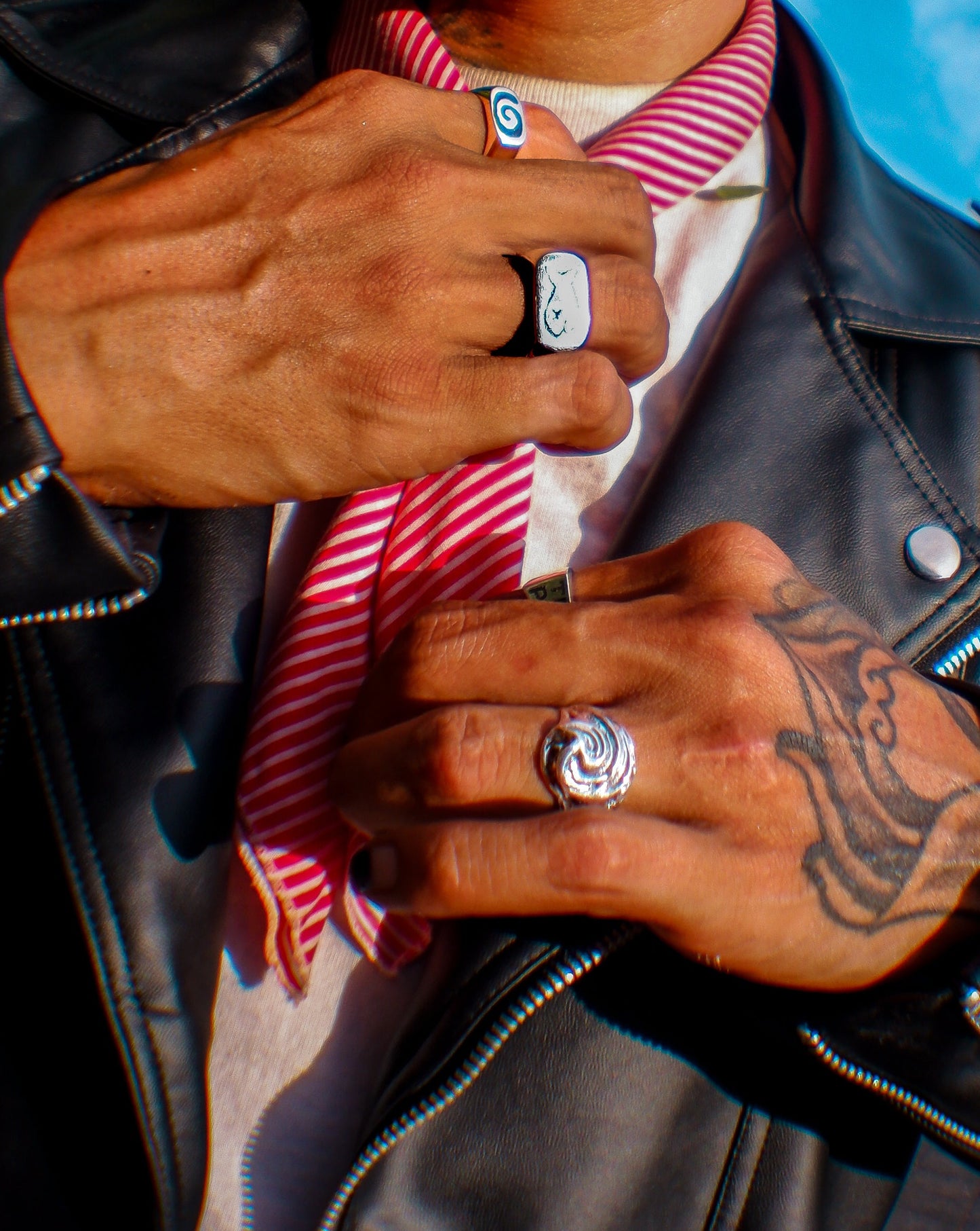Silver Tidal Wave ring pictured on a person wearing a black leather jacket with a red and white striped tie.