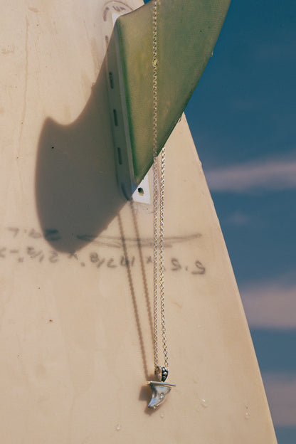 SURFBOARD FIN, Necklace with a pendant on a surfboard fin with a blue sky background