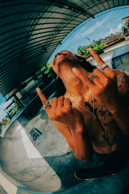 Model in Skatepark looking up smiling with Rock and roll hands with the Black Sand Spiral Signet, Rockstar Pendant, Teach Peace Ring, and the Badfish Ring